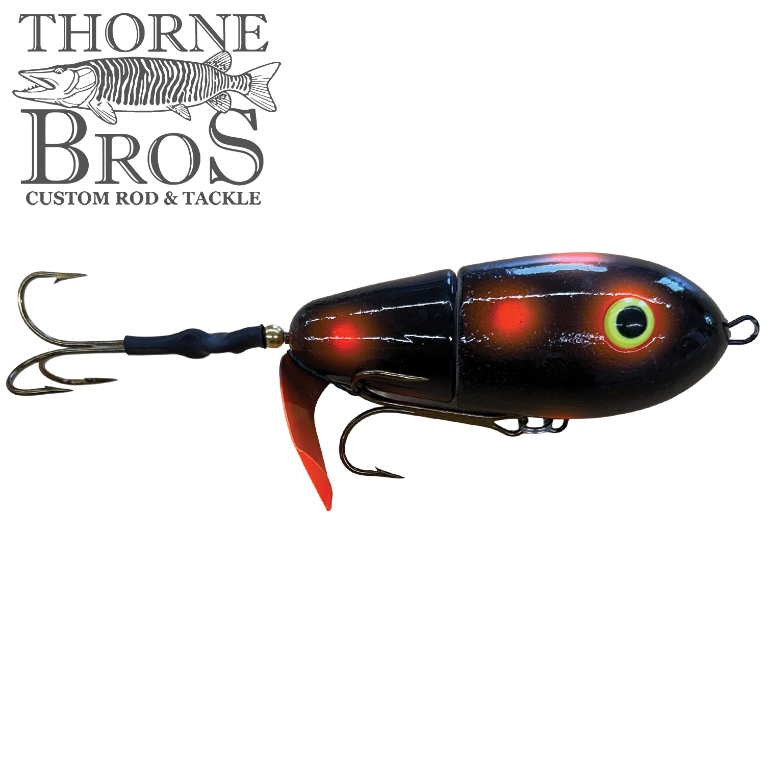 Lake-X Fat Bastard fishing lure featuring a segmented black and red body, bright eye detail, and two sharp treble hooks, designed for musky fishing tackle.