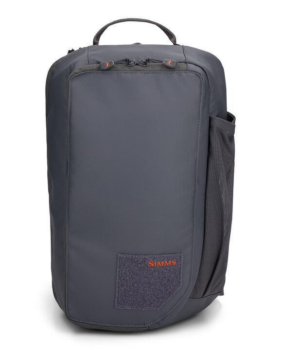 Simms Tributary Sling Pack in dark gray with a streamlined design, front zippered pocket, side mesh pocket, top handle, and embroidered logo, ideal for fishing tackle organization.