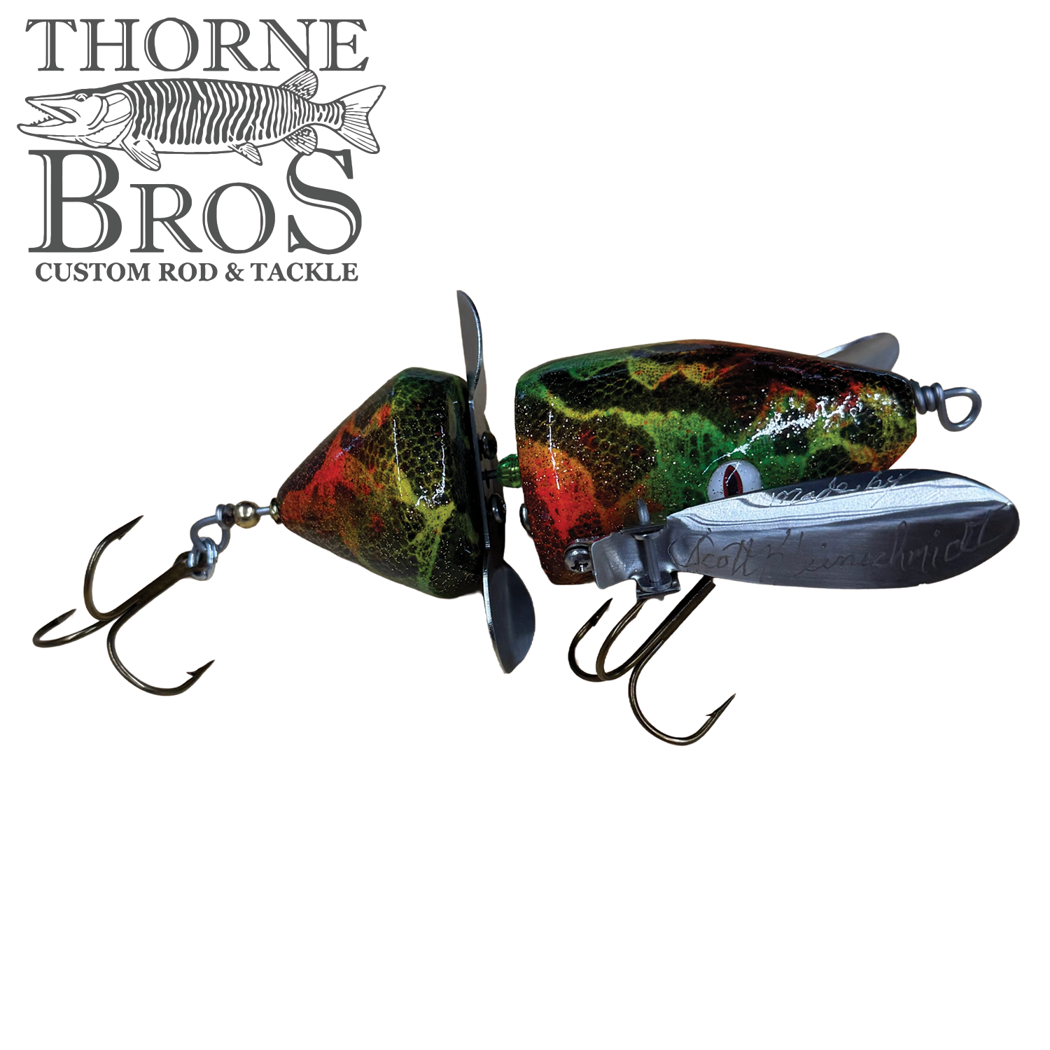 Musky Safari Mini Baby Spitzer fishing lure with green, red, and black camo pattern, equipped with two treble hooks and metal propellers for musky fishing.
