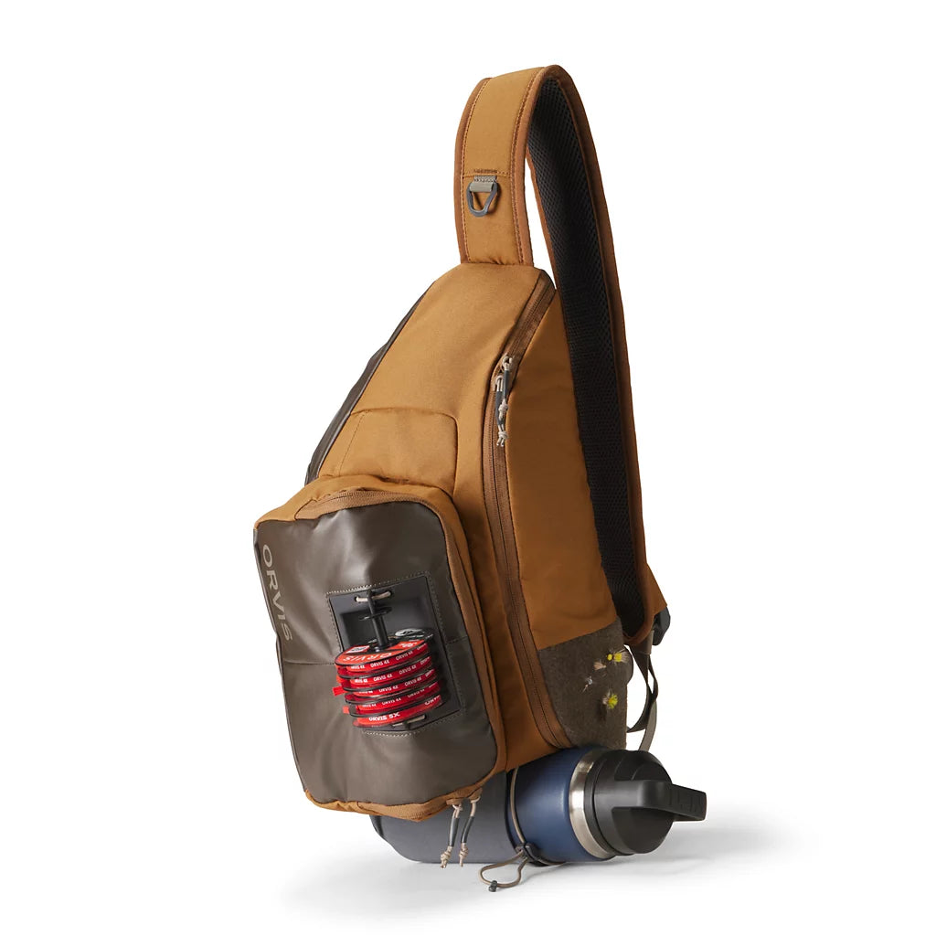 Orvis Sling Pack in brown with front fly box holder and attached water bottle for convenient fishing tackle storage and hands free stream access