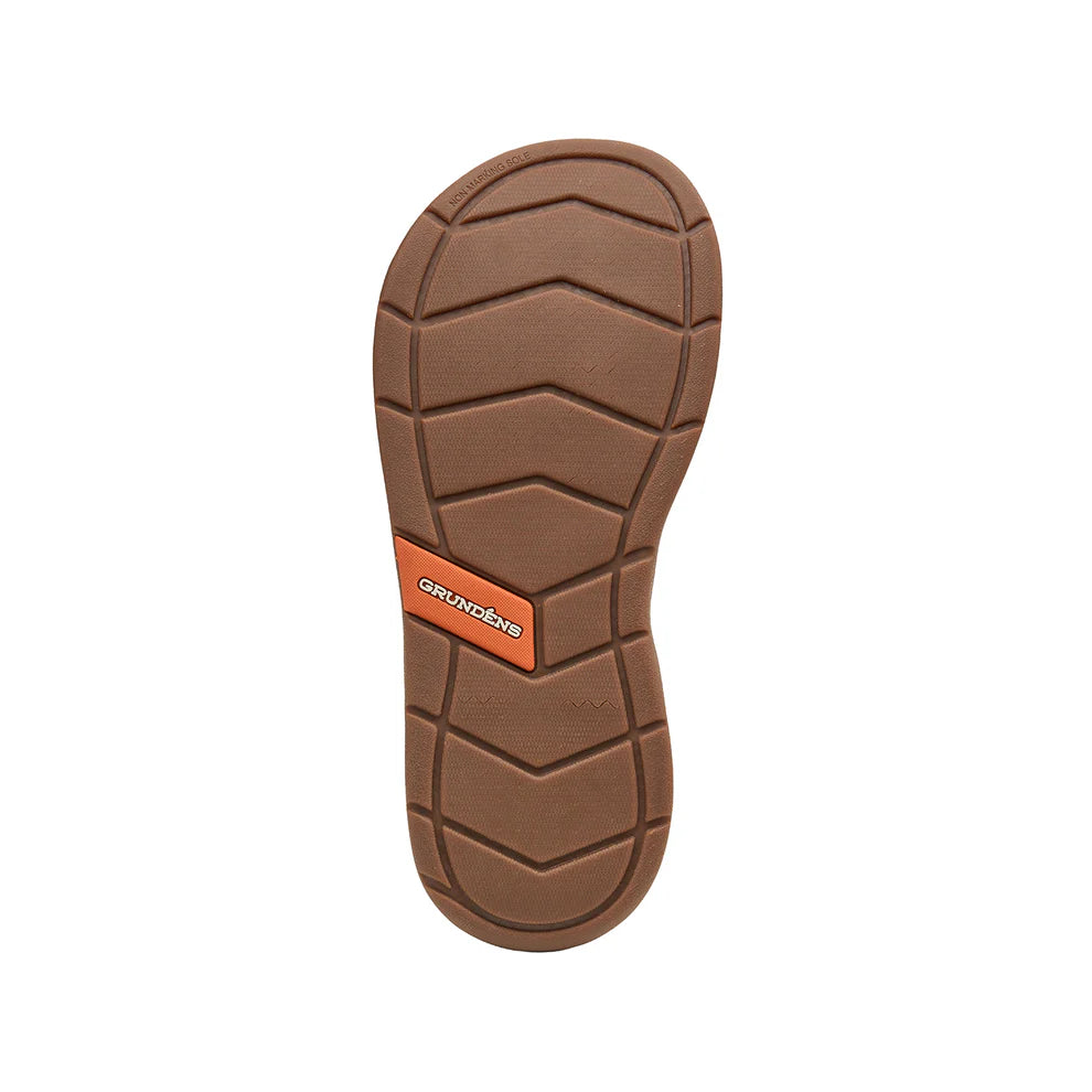 Grundens Deck Boss Sandals shown from the sole view, featuring a durable brown tread pattern with an orange logo accent designed for reliable traction in fishing and outdoor environments.