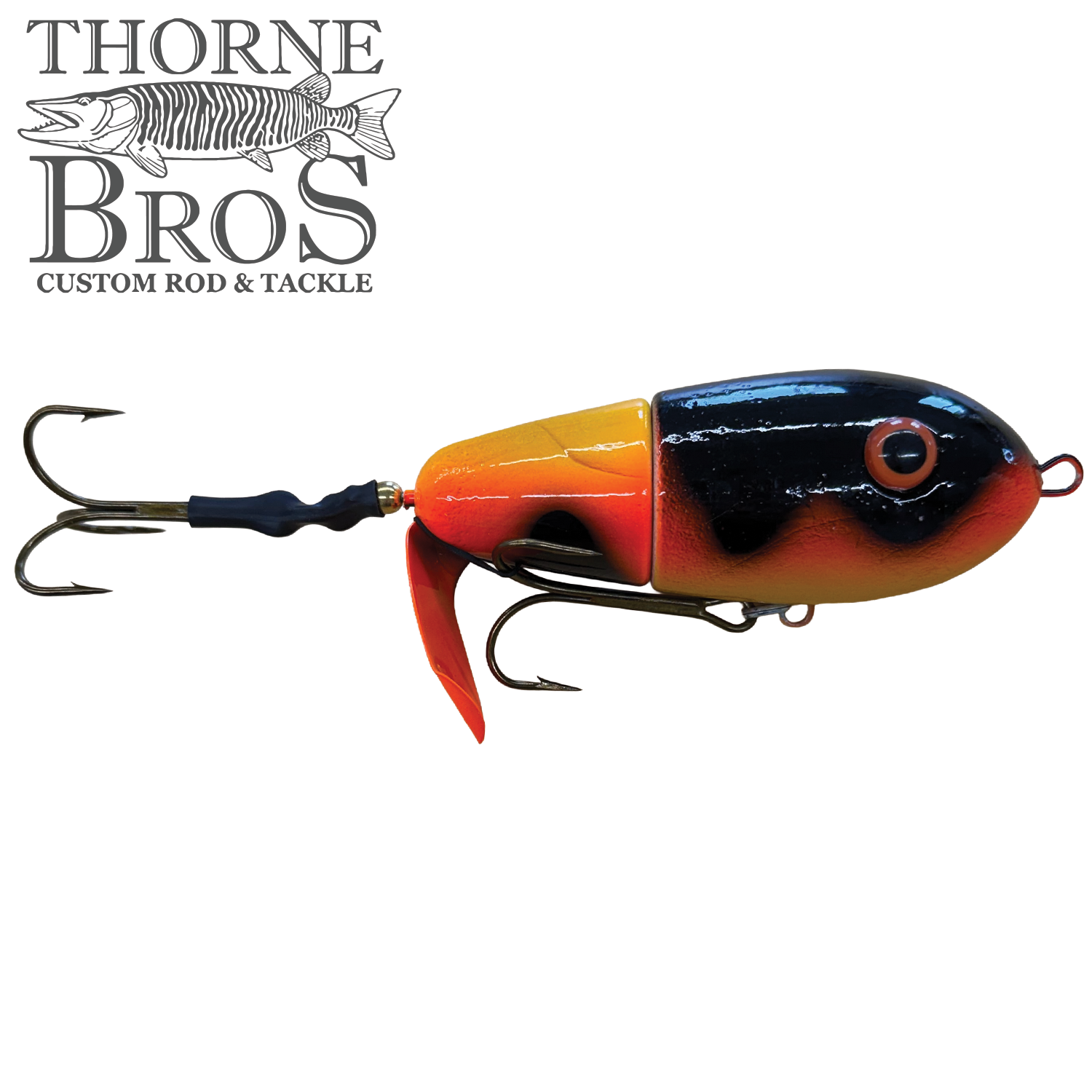 Lake-X Fat Bastard fishing lure with a segmented body in black and orange colors, featuring two treble hooks and a red plastic fin for musky fishing tackle.