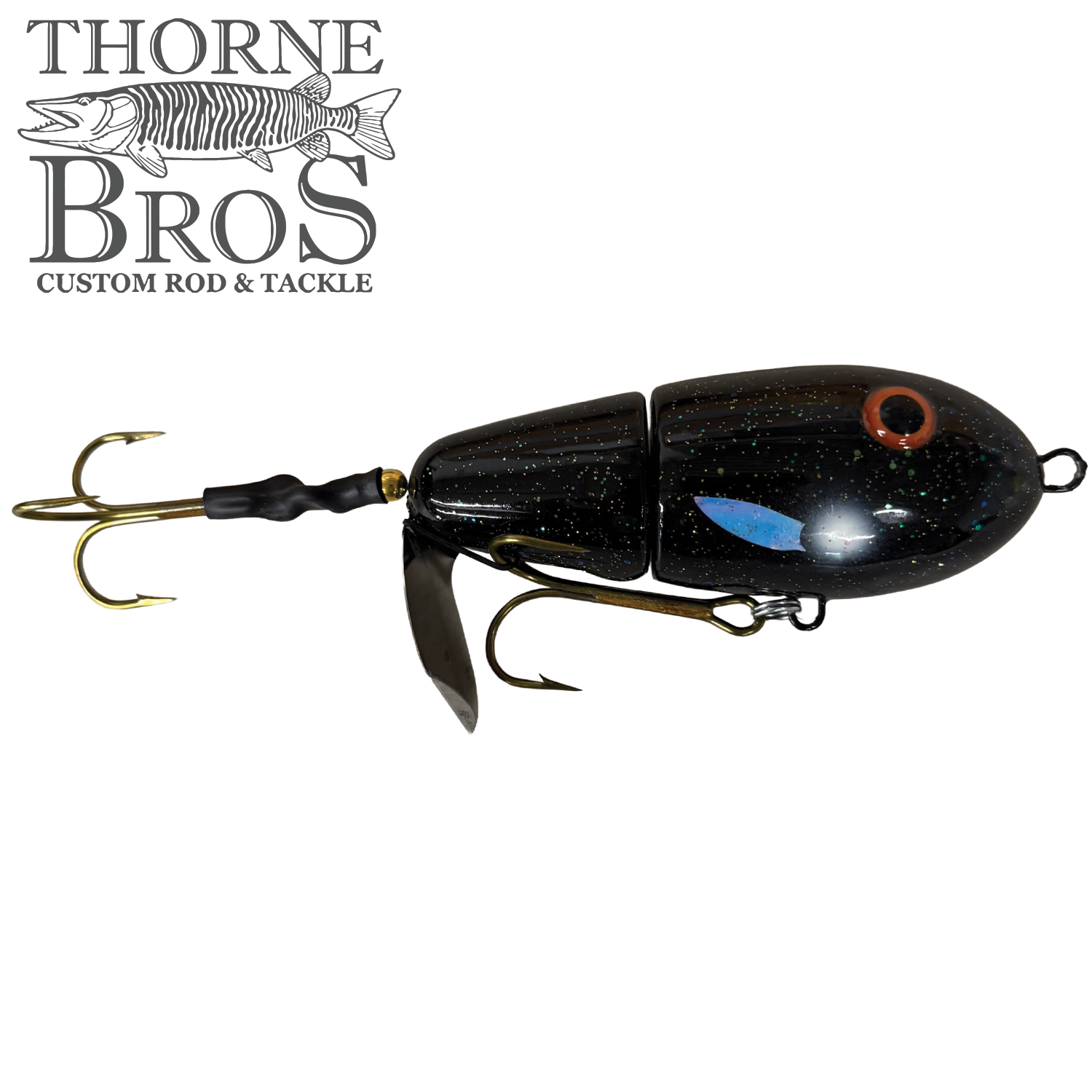 Lake-X Fat Bastard fishing lure in black with glitter accents, featuring a segmented body, two treble hooks, and a metal blade for musky fishing.