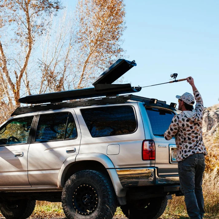 Trxstle ARC Fishing Rod Carrier mounted on an SUV while an angler loads a fishing rod for convenient outdoor fishing gear transport