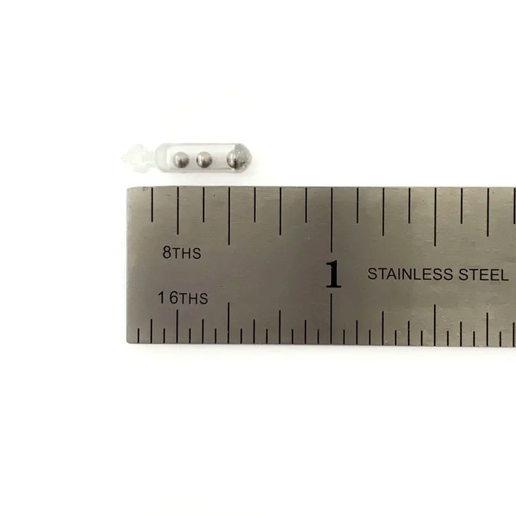 Clear plastic tubular fishing accessory containing three small metal balls next to a stainless steel ruler showing its compact size, identified as Sight Cast Mini Rattles.