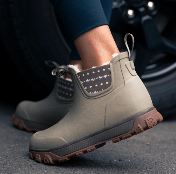 Grundens Women's Deviation Sherpa Ankle Boot in tan with cozy patterned sherpa lining pull tabs and rugged lug soles shown worn outdoors