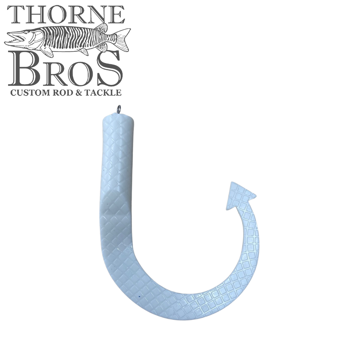 White fishing lure shaped like a curved tail with textured pattern and a small loop for attachment, labeled as Boss Shad Hybrid Tails for use with fishing tackle.