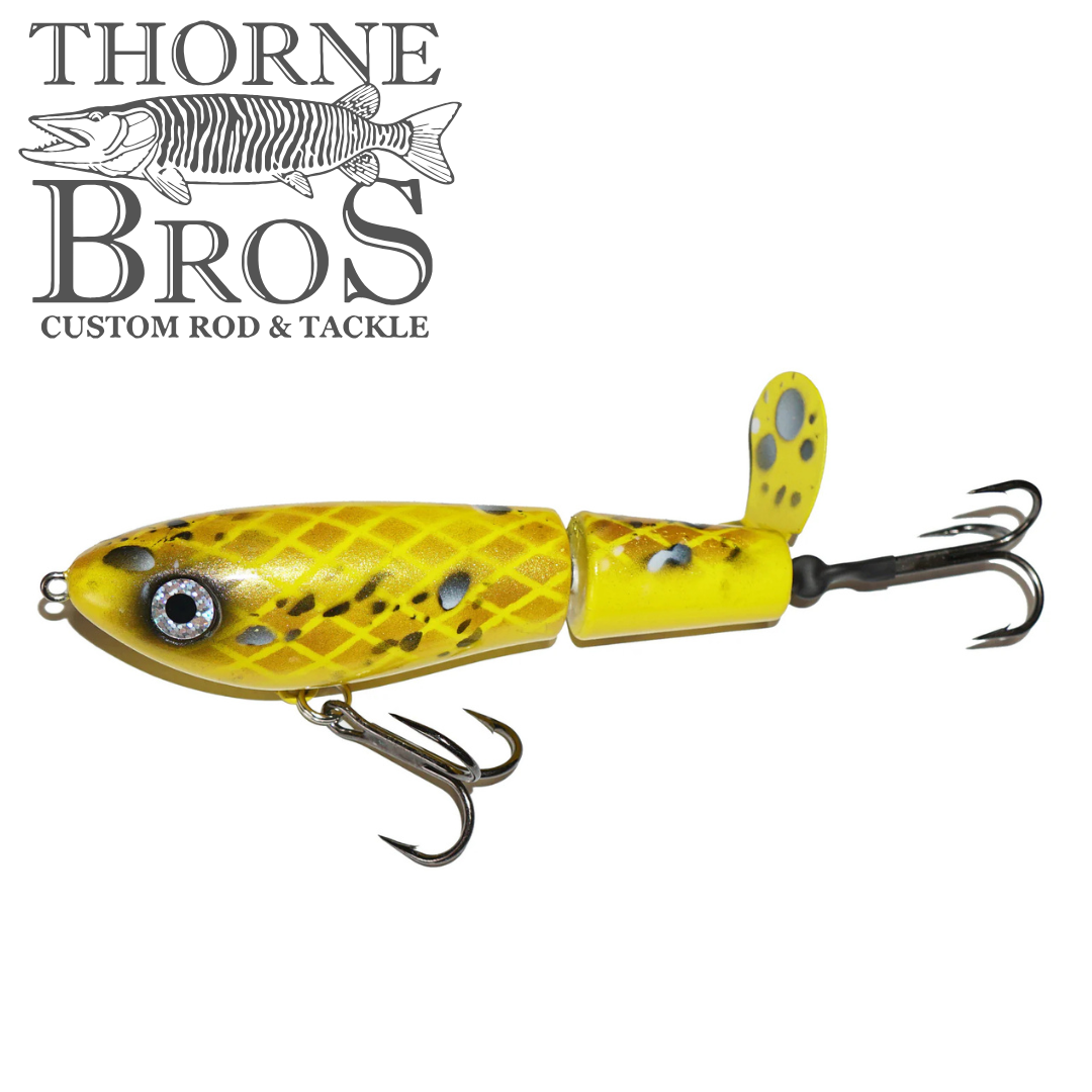 Bucher Topraider fishing lure in bright yellow with black spots, featuring two treble hooks and a small propeller tail designed for musky fishing tackle.