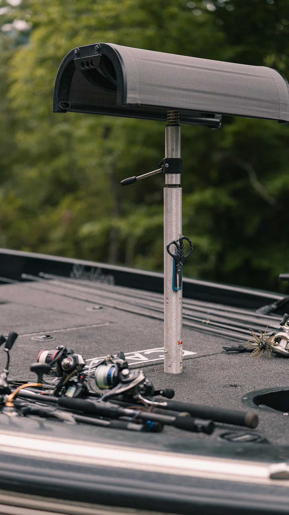Cling Tool Stick Mini attached to a boat seat post with black fishing scissors hanging on it, fishing rods and reels positioned on the boat deck in the background.