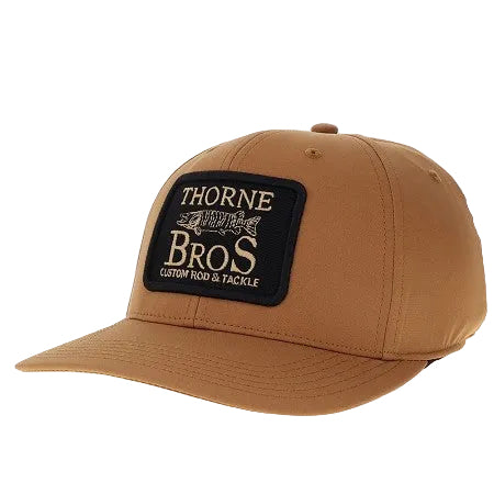 Thorne Bros. Logo Back Nine Hats in tan color featuring a structured front panel with a black patch displaying the Thorne Bros. brand name and a fish graphic, designed for fishing enthusiasts.