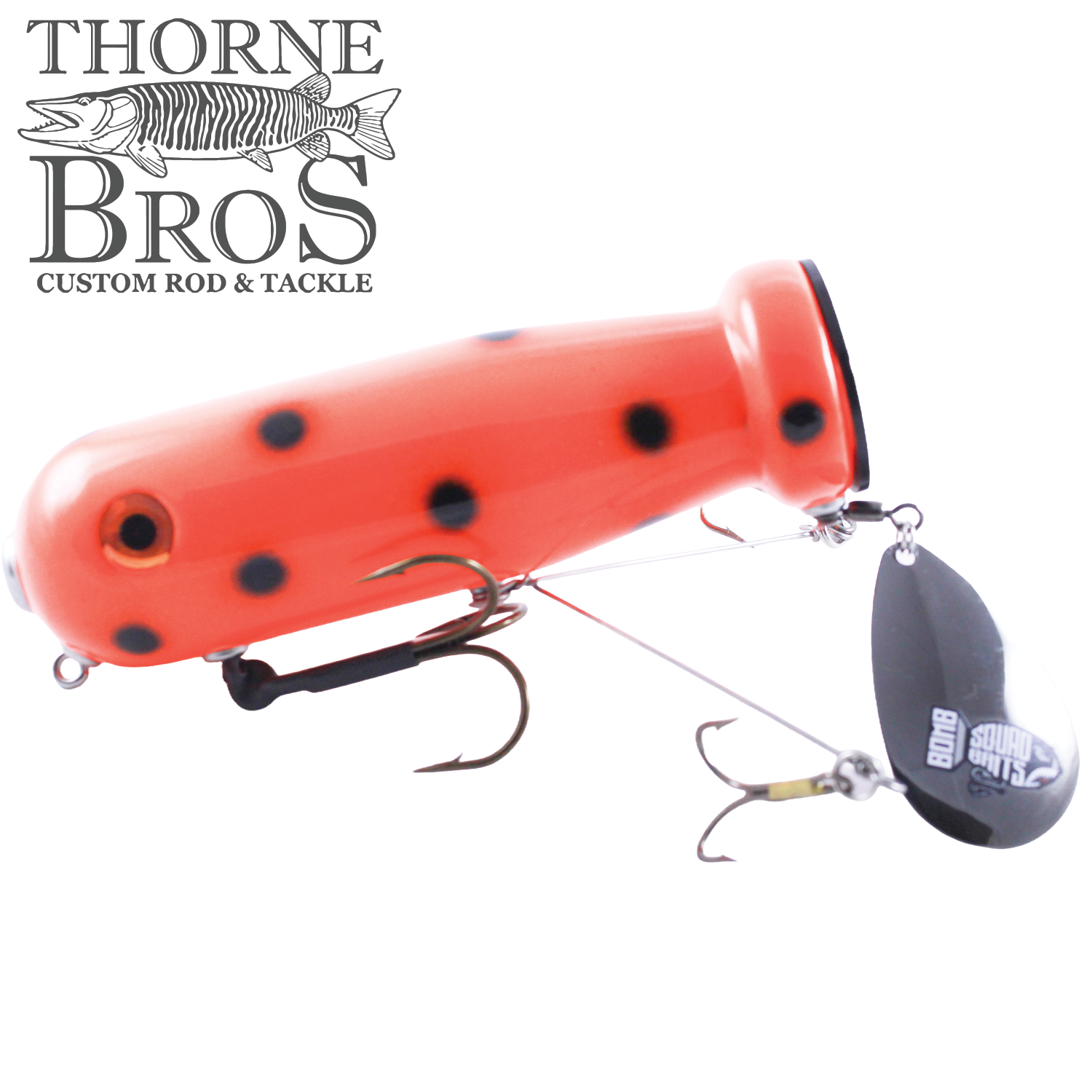 Bright orange fishing lure with black spots, featuring two treble hooks and a spinning black flap tail blade, designed for musky fishing, labeled Bomb Squad MK-65 Flap Tail.