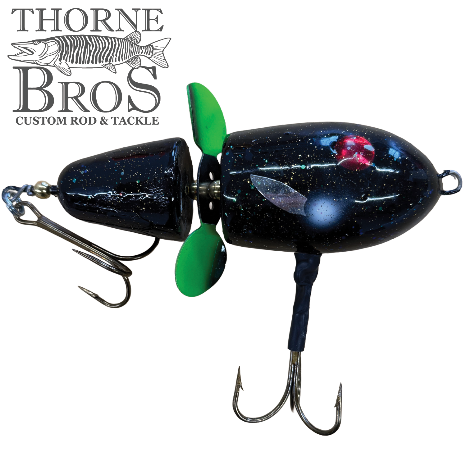 Close-up of a black Lake-X Hammer fishing lure with green propeller, two treble hooks, and detailed painted accents resembling underwater elements, designed for musky fishing.
