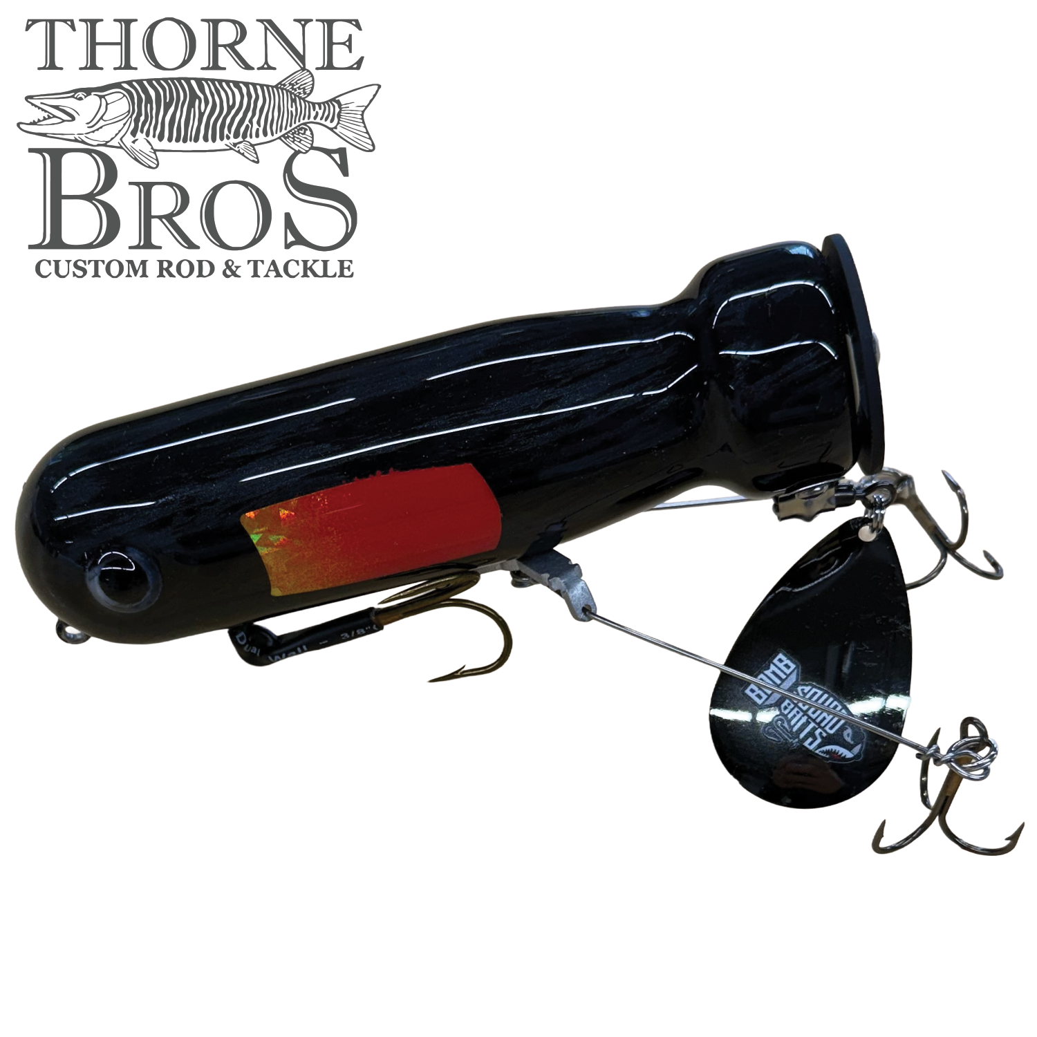Bomb Squad MK-65 Flap Tail fishing lure in black with red accent, featuring dual treble hooks and a metal flap tail spinner for musky fishing tackle.