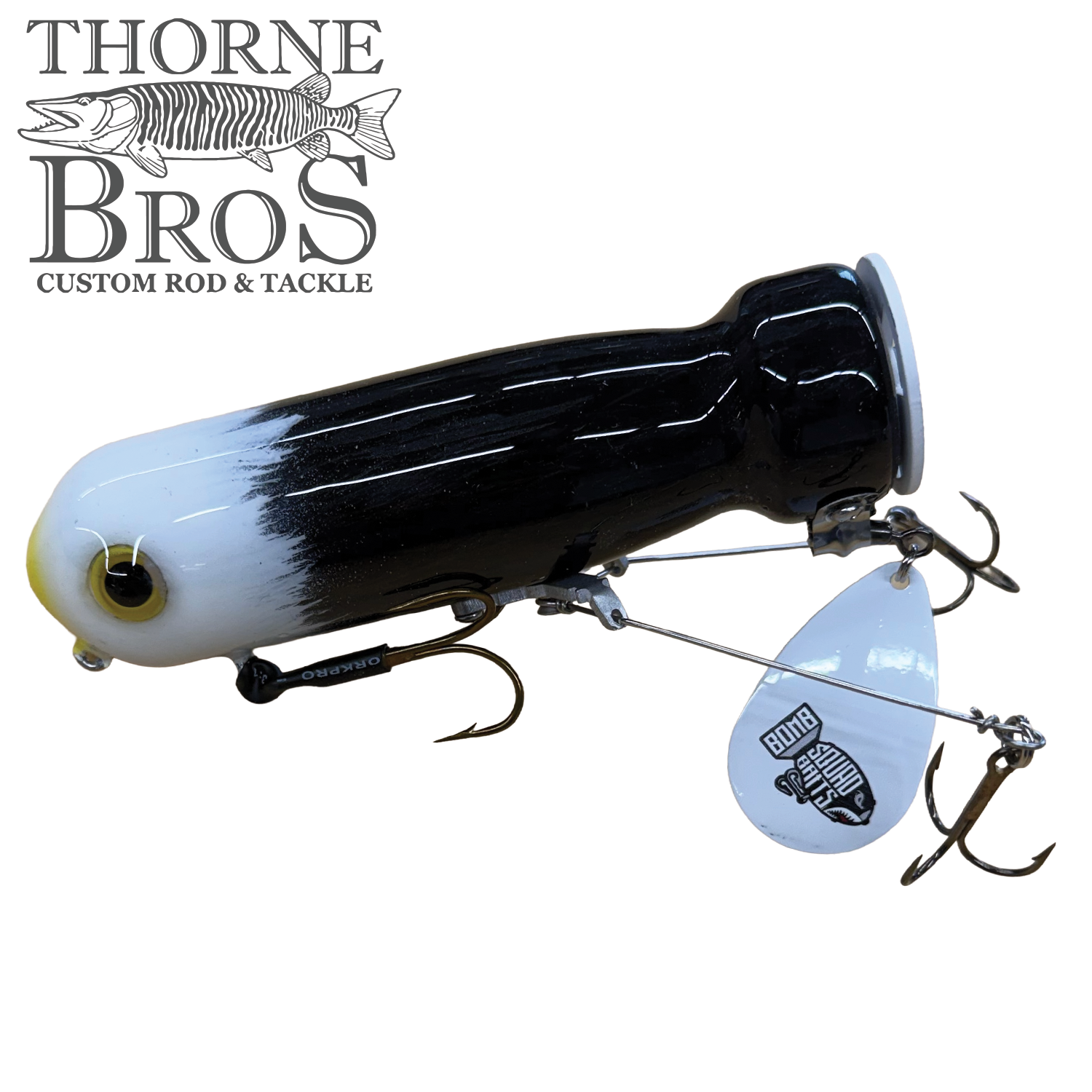 Bomb Squad MK-65 Flap Tail fishing lure in black and white with multiple treble hooks and a metal spinner blade, designed for musky fishing.