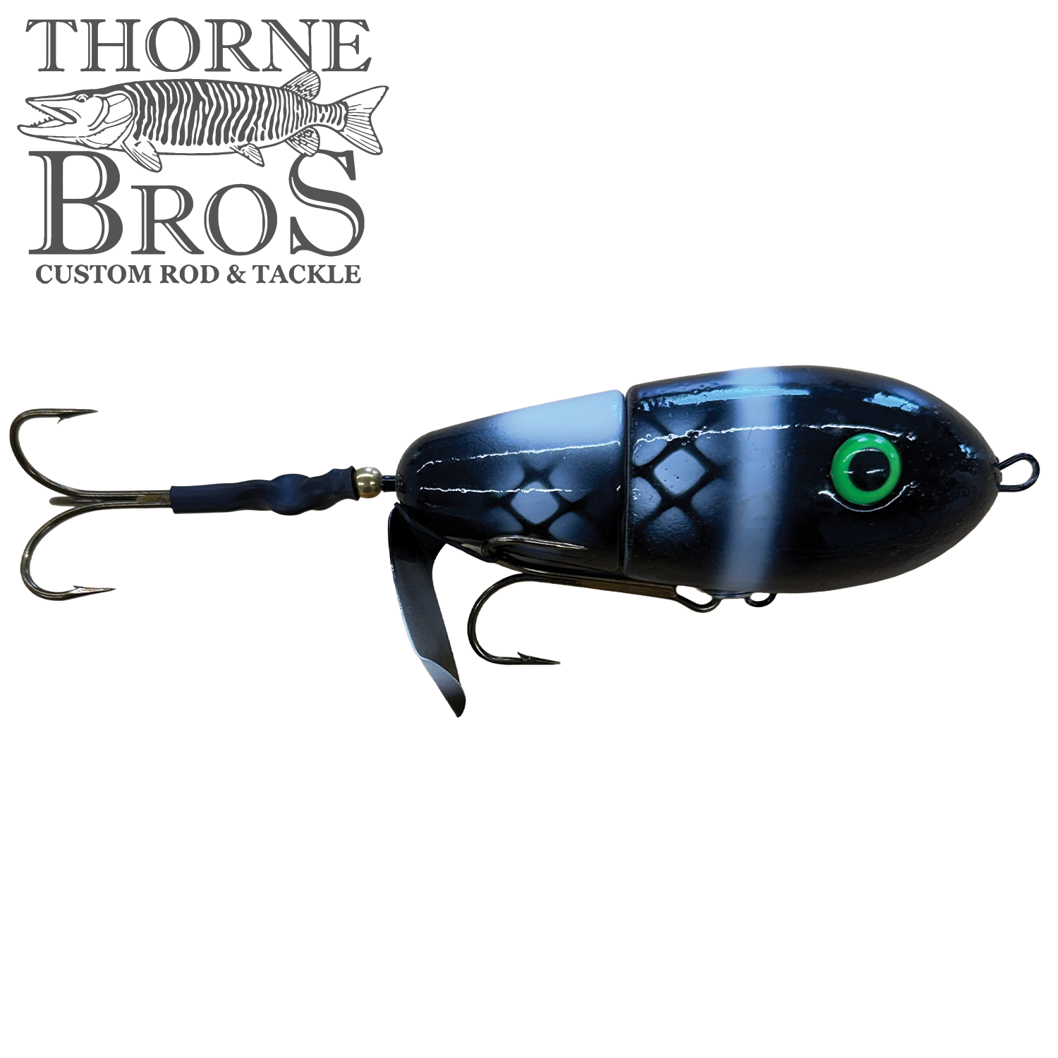 Lake-X Fat Bastard musky fishing lure in black with white stripes and scale pattern, featuring green eye detail, metal treble hooks, and a propeller-style tail for realistic water action.