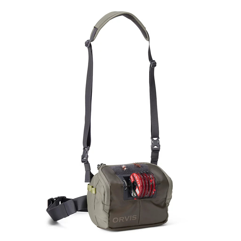 Orvis Chest/Hip Pack in olive green with adjustable shoulder and waist straps plus a front pocket holding a red fishing line spool