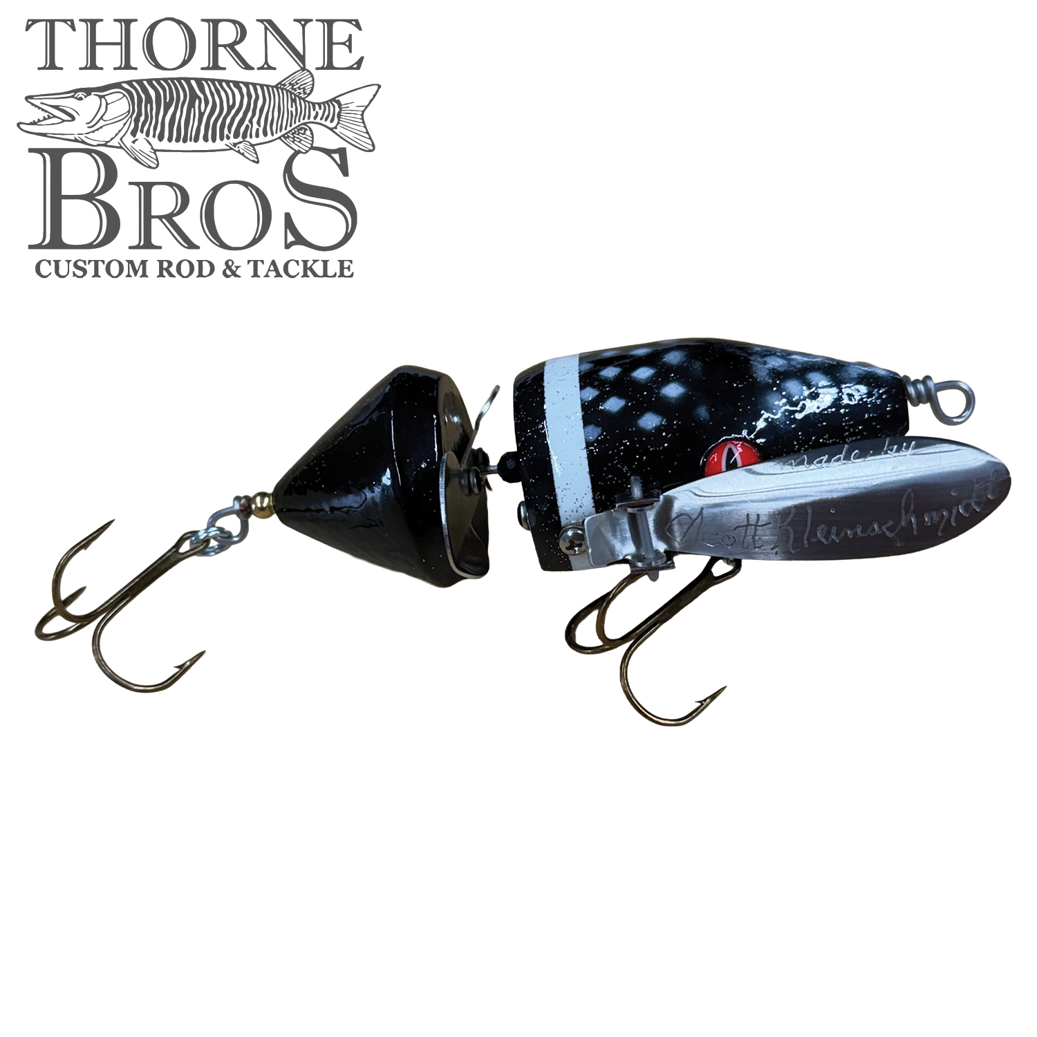 Musky Safari Mini Baby Spitzer fishing lure in black with white accents, featuring two treble hooks and a silver spinner blade, designed for musky fishing tackle.