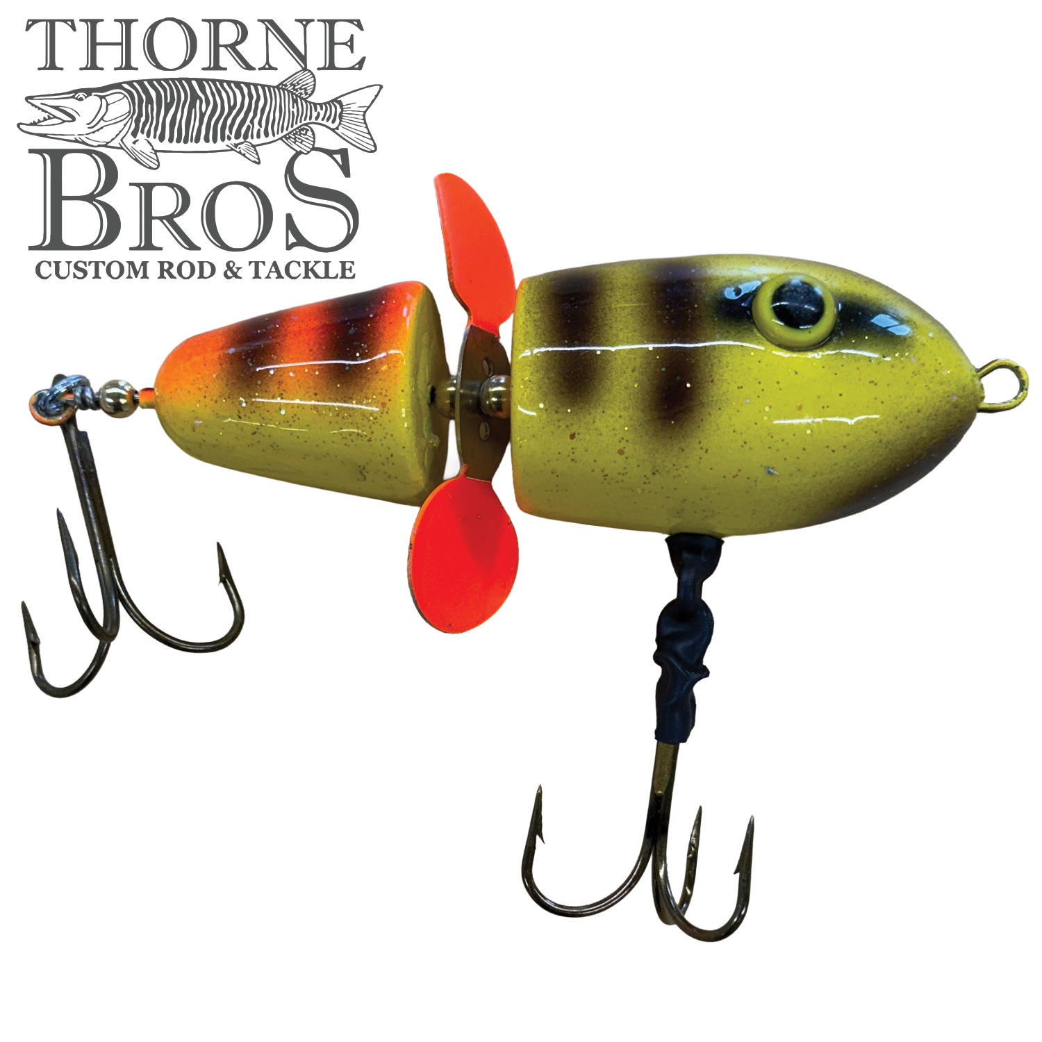 Close-up of the Lake-X Hammer fishing lure in yellow and orange with black stripes, featuring two treble hooks and a red propeller in the middle for enhanced water action.