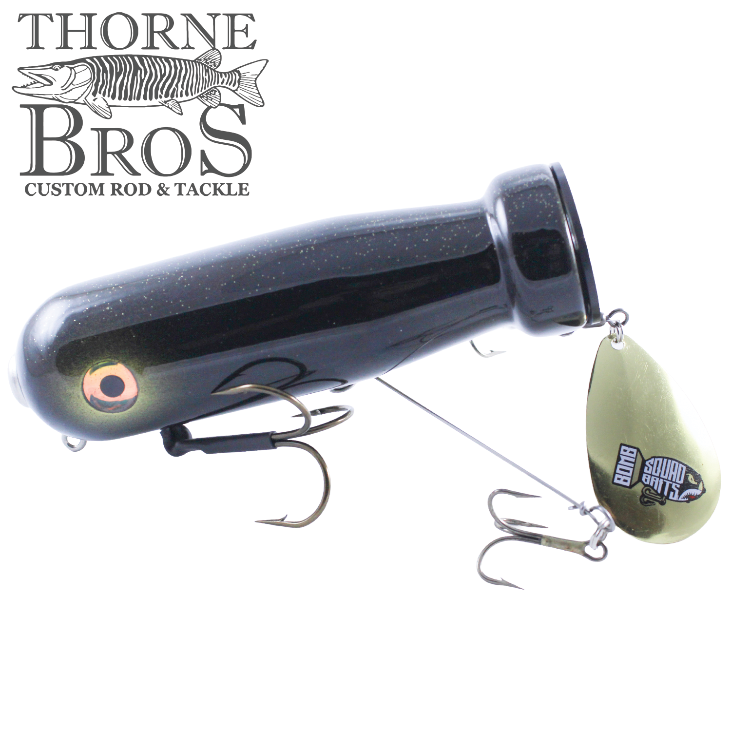 Bomb Squad MK-65 Flap Tail fishing lure in black with a reflective eye design, featuring two treble hooks and a metallic spinner blade branded with Bomb Squad Baits.
