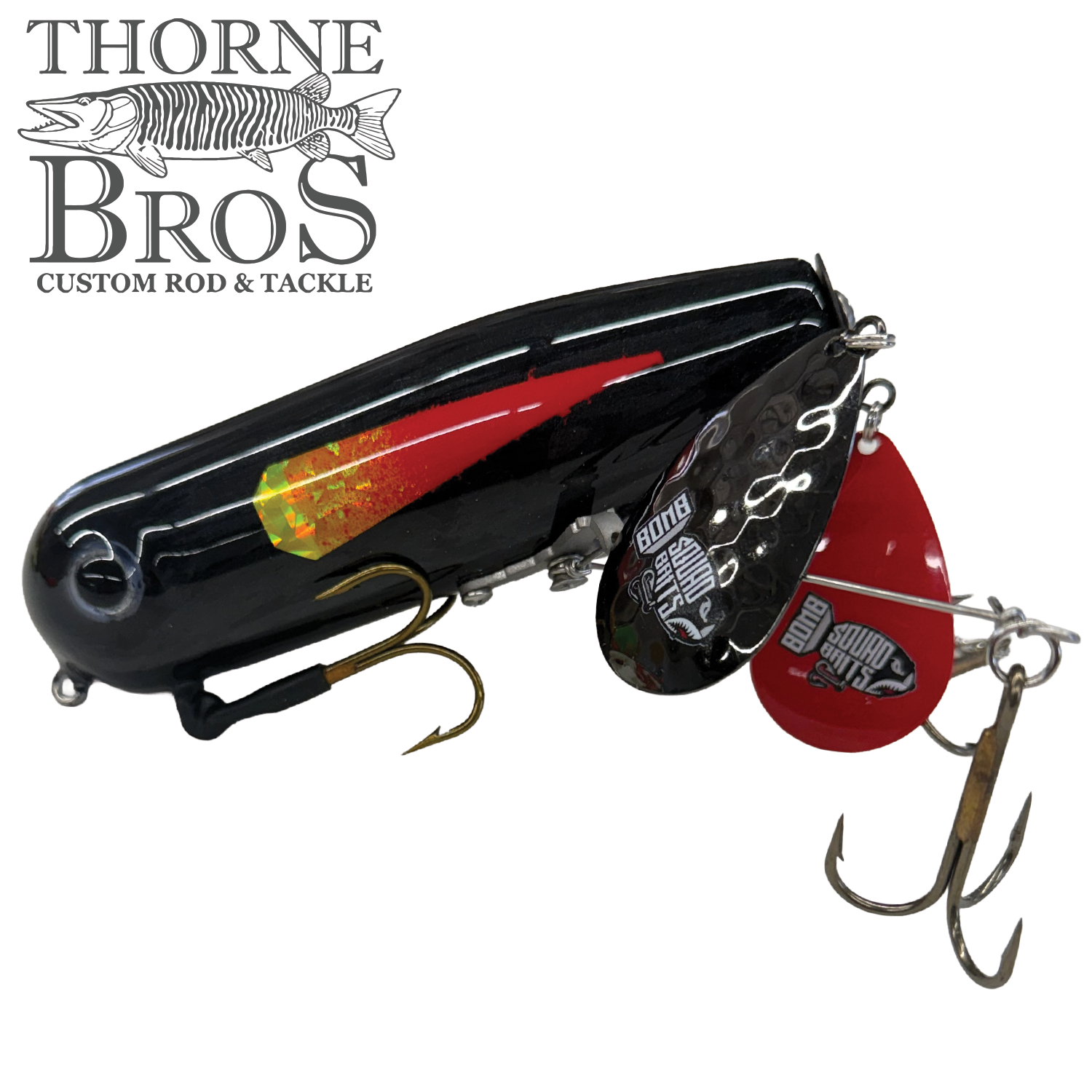 Bomb Squad Double Tap Flap Tail fishing lure with a black body, red and yellow accents, dual metal flap tails, and sharp treble hooks designed for musky fishing.