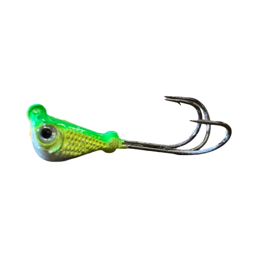 Close-up of a green and yellow Mission Tackle Grabber Jig fishing lure with a detailed fish head design and two sharp metal hooks for fishing tackle use.