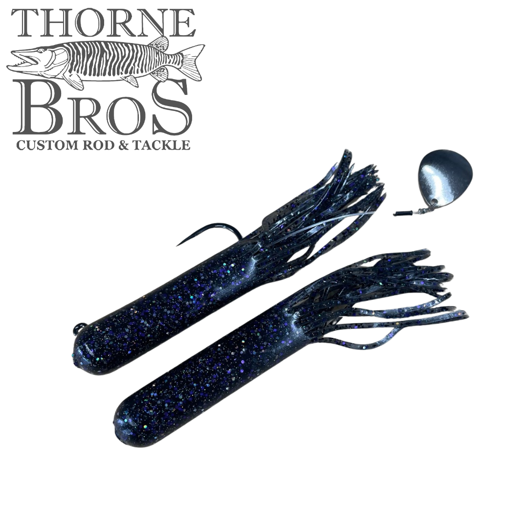 Two dark blue Drop Tine Chunker Tubes fishing lures with glittery specks, featuring multiple flexible skirt strands and one lure with an attached silver spinner blade.