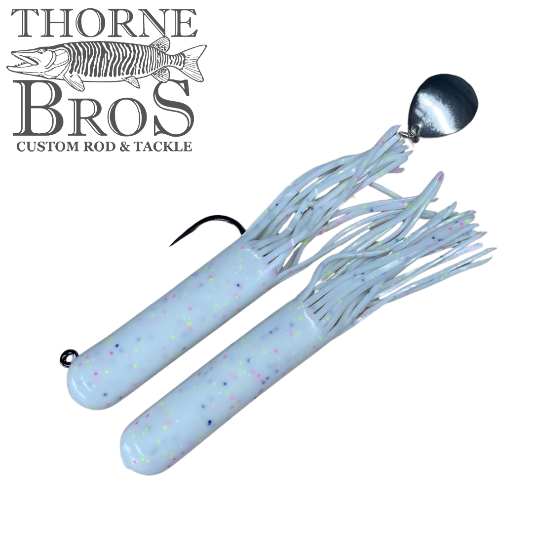 Two white Drop Tine Chunker Tubes fishing lures with colorful speckles, one featuring a metal spinner blade and silicone skirt strands for musky fishing.