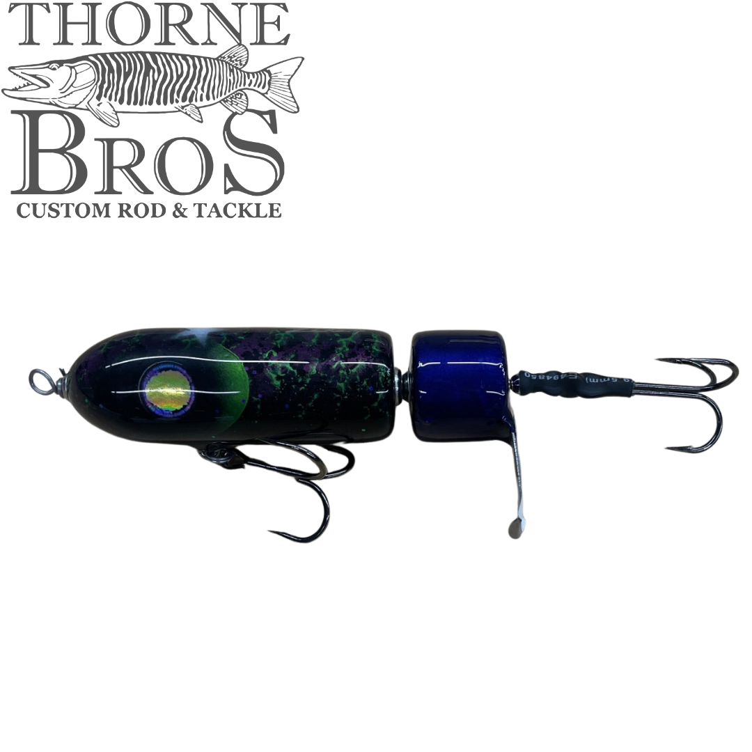 Zilla Baits PropWash black and blue topwater musky fishing lure with treble hooks and a tail propeller displayed on a white background