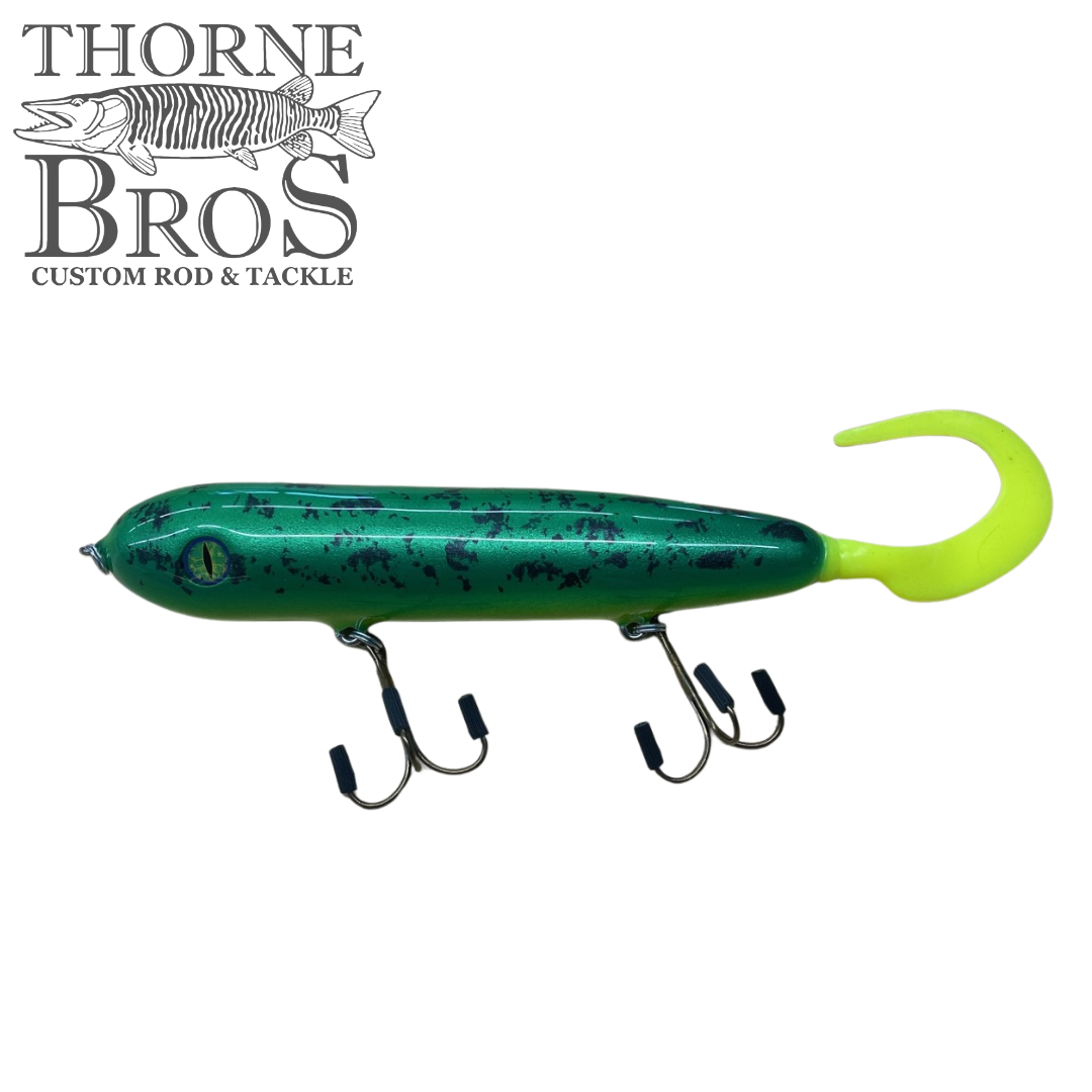 Holmgren Serpent Musky Top Water fishing lure in green with black speckles and bright yellow tail, featuring two treble hooks, designed for musky fishing.