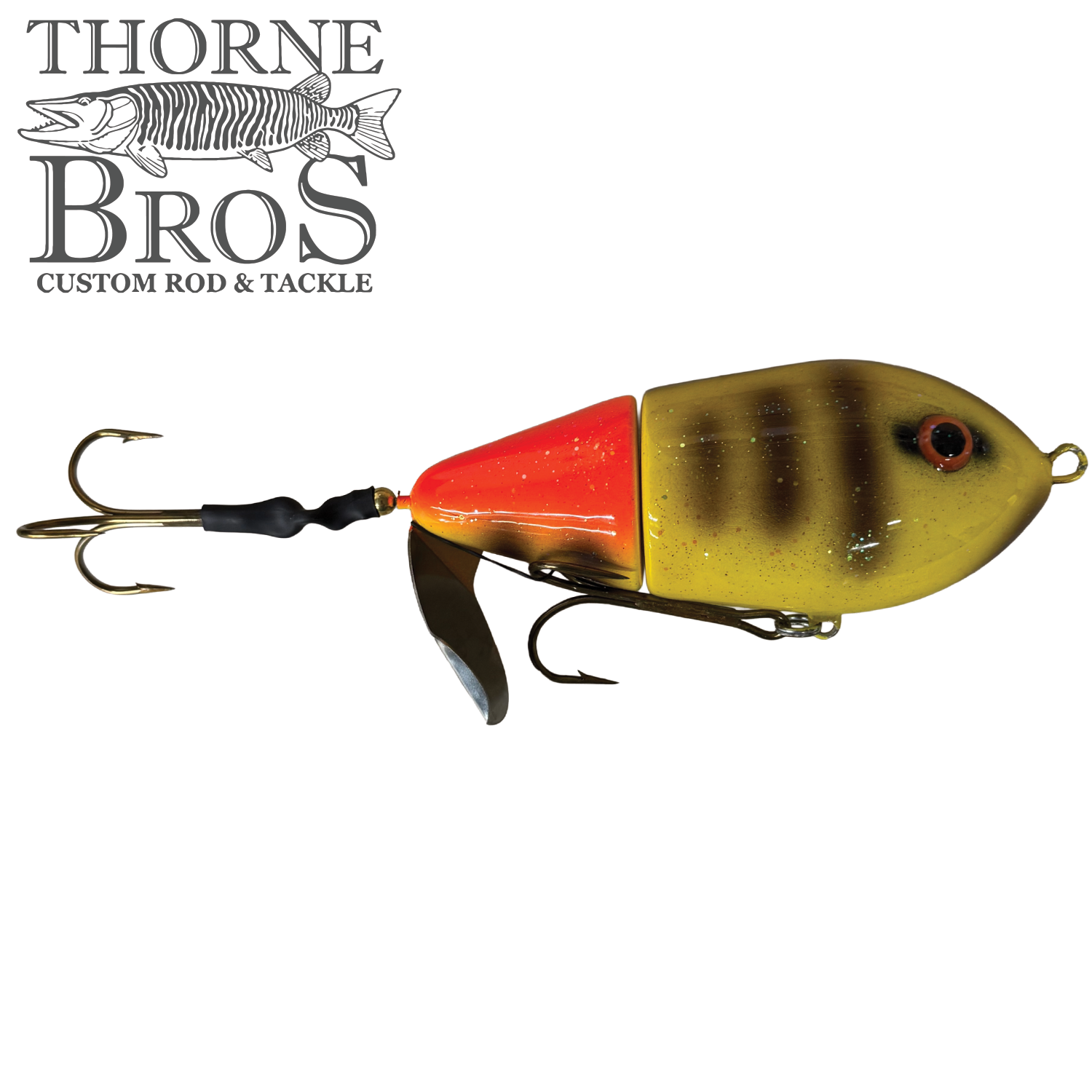 Close-up of the Lake-X Cannonball JR. fishing lure featuring a segmented yellow and orange body with black stripes, realistic red and black eye, two sharp treble hooks, and a metal spinner blade, designed for musky fishing.